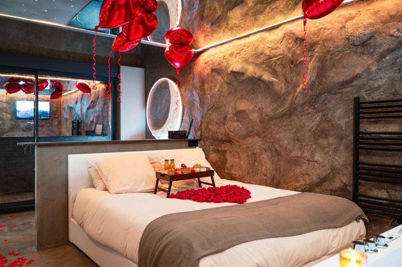 Chambre romantique avec pétales de roses, ballons et petit-déjeuner